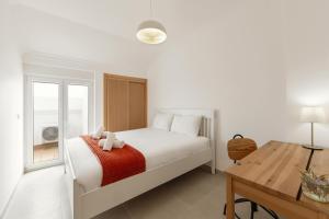 a white bedroom with a bed and a table at Baleal Oceanviews in Ferrel