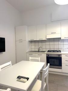 a kitchen with white cabinets and a white table with chairs at The Giza House in Olbia
