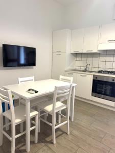 a white kitchen with a white table and chairs at The Giza House in Olbia