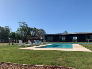 a swimming pool with two lawn chairs and a house at Establecimiento Don Elder in Sunchales