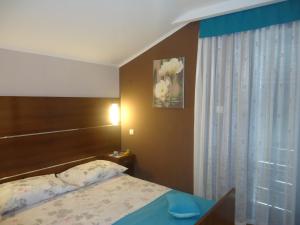una camera da letto con un letto con testiera in legno e una finestra di Apartments Barbara a Pinezići
