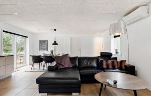 a living room with a black leather couch and a table at 3 Bedroom Beautiful Home In Tarm in Tarm