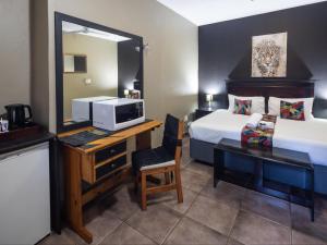 a hotel room with a bed and a desk with a television at Eco Lodge Lephalale in Lephalale
