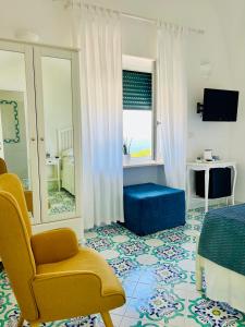a bedroom with a yellow chair and a blue ottoman at B&B L'Agapanto in Capri