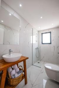 a white bathroom with a sink and a toilet at Kanes Boutique Hotel in Sarandë