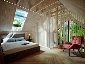 a bedroom with a bed and a chair and a window at Baltico Stodoła in Mielno