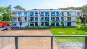 a large white building with a parking lot at Rezydencja Niechorze D206 Eco Boho - 5D Apartments in Niechorze