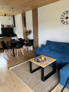 a living room with a blue couch and a table at Domki Rewal kalimera-sun in Rewal