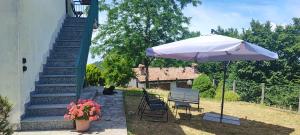 a patio with a table and an umbrella and stairs at Casa vacanza Da Lara in Poggio Ferrato