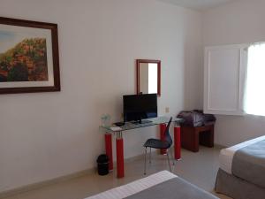 a bedroom with a desk with a television and a bed at Zar San Luis Potosi in San Luis Potosí
