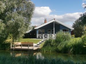 a blue house with a dock next to a lake at 6 Personen Ferienhaus mit privatem Bootsteg, dikekter Seelage, Kanu, Whirlpool, Sauna und Kaminofen in Otterndorf in Otterndorf
