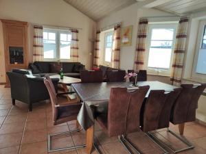 a living room with a wooden table and chairs at 6 Personen Familienferienhaus mit Sauna, Whirlpool zwei Toiletten und Kaminofen in Otterndorf in Otterndorf