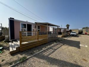 a house with a porch and a car parked in front of it at Camping Le Littoral in Le Grau-dʼAgde