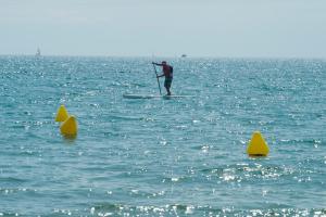 a man standing on a paddle board in the water at Camping Le Littoral in Le Grau-dʼAgde