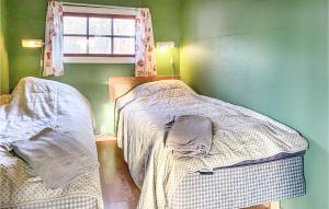 two beds in a green room with a window at Lasses Stuga in Visby