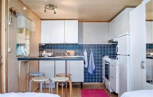 a small kitchen with white cabinets and blue tiles at Lasses Stuga in Visby