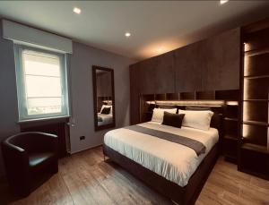 a bedroom with a large bed and a chair at La Tana Del Ludo in Baveno