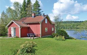 a red house on a lawn next to a lake at 3 Bedroom Cozy Home In Åmål in Åmål