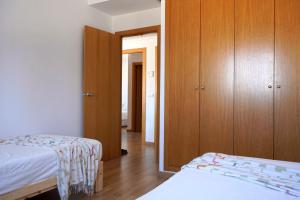 - une chambre avec 2 lits et des placards en bois dans l'établissement Appartement lumineux proche Valencia - À 10 min de la mer !, à Puebla de Farnals