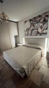 a bedroom with a bed and a painting on the wall at HomeStyle Agorà in Villasimius