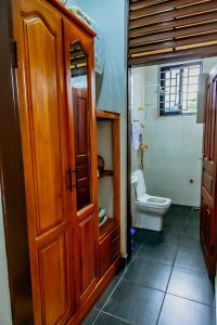 a bathroom with a toilet and a wooden cabinet at Bellevie Homestays in Uru