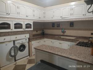 a kitchen with white cabinets and a washer and dryer at Mogadorista pour les familles in Essaouira