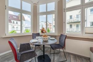 einen Tisch und Stühle in einem Zimmer mit Fenstern in der Unterkunft Villa Carmen Strandkorb in Ahlbeck