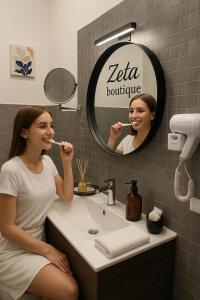 a woman brushing her teeth in front of a bathroom sink at Zeta Boutique in Caserta