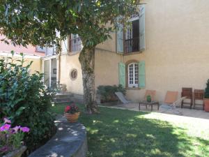 una casa con sedie e un albero nel cortile di Le Clos de la Bastide a Galan