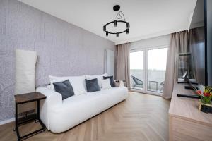 Manufaktura Suites - 76m2, Parking, AirCon - by Rentujemy في لودز: غرفة معيشة مع أريكة بيضاء وطاولة
