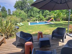 a deck with chairs and an umbrella and a pool at Maison au calme in Saramon