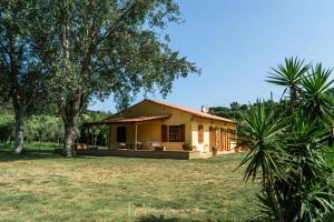 a small yellow house in a yard with trees at Podere Il Ritorno in Portoferraio