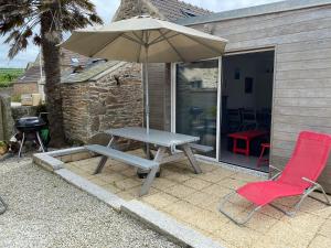 a picnic table with an umbrella and two chairs at Gite du Becquet in Le Rozel