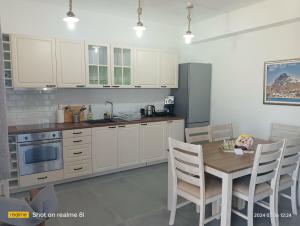 斯基罗斯岛Méliris house的厨房配有白色橱柜和桌子及椅子