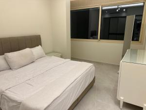 ein Schlafzimmer mit einem weißen Bett und einem Fenster in der Unterkunft Water Front Luxury in Jnah Beirut  + 6 Fotos