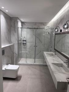 ein Bad mit einer Dusche, 2 Waschbecken und einem WC in der Unterkunft Water Front Luxury in Jnah Beirut 