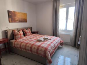 a bedroom with a bed with a plaid blanket and a window at Maison au coeur de Banon in Banon