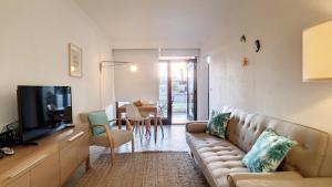 a living room with a couch and a television at Tróia 2 Minutes from the Beach in Troia
