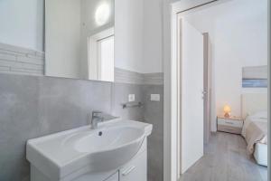 a white bathroom with a sink and a bed at Il Faraglione in Noto Marina +37 photos