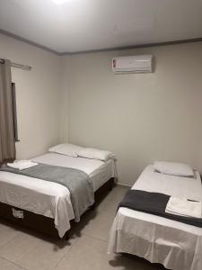 two beds in a room with white walls at Hotel King Palace - Hotel Irituia in Irituia
