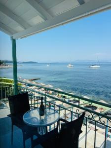 a table with a bottle of wine sitting on a balcony overlooking the ocean at Avra Benitses Beach Apartment in Benitses