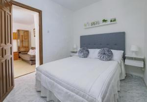 una camera da letto con un grande letto bianco con due cuscini blu di Cubo's Casa Rural El descanso del Caminito del Rey ad Ardales