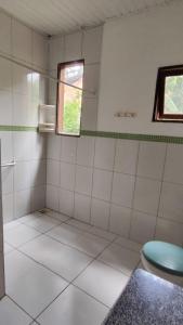 パウメイラスにあるCasa Amorの白いタイル張りのバスルーム(窓、トイレ付)