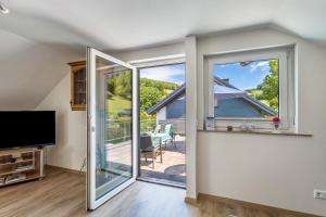 ein Wohnzimmer mit einer Glasschiebetür, die auf eine Terrasse führt in der Unterkunft Ferienwohnung Am Waldrand in Schmallenberg
