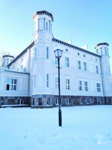 a large white building with a street light in the snow at Pałac Lubiechowo in Lubiechowo +4 photos