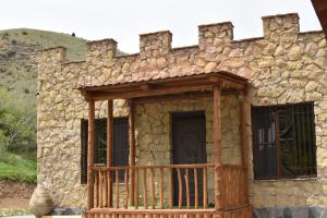 a small stone building with a porch and a balcony at Cottage near Noravank, Areni, Sauna, Wine in Areni