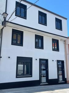 a white building with black windows and doors at Camiño da Camposa in Muxia