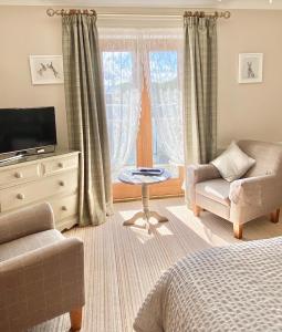 a bedroom with a bed and a chair and a tv at Springwood Room Only Accommodation in Seahouses
