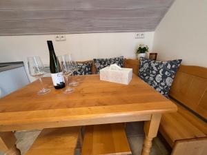 a wooden table with two glasses and a bottle of wine at Apartmány Kutěj in Mutěnice