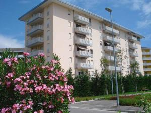 wysoki budynek apartamentowy z różowymi kwiatami przed nim w obiekcie Apartment in Porto Santa Margherita 42874 w mieście Porto Santa Margherita di Caorle